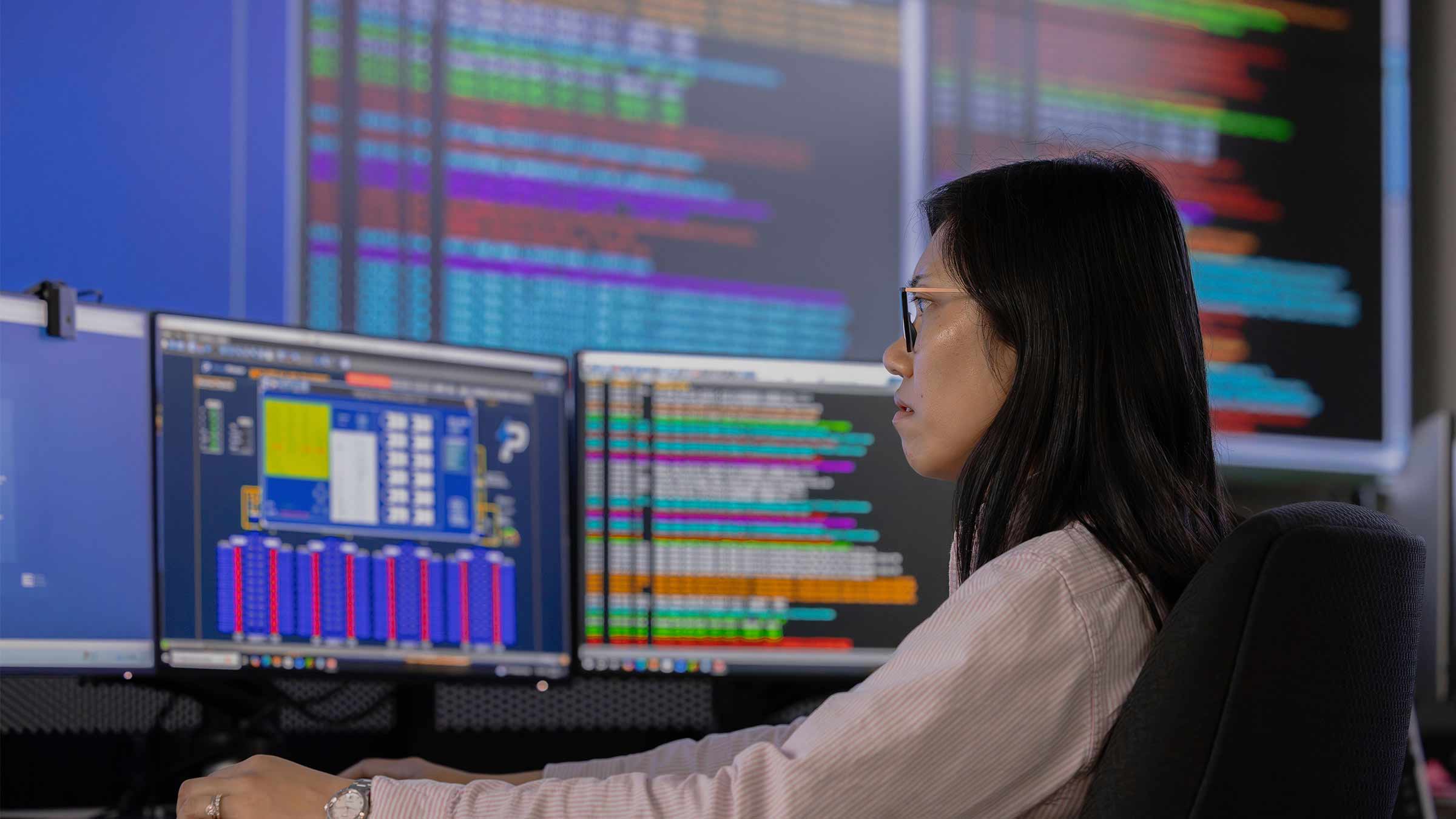 Energy analyst monitoring data across multiple computer screens.